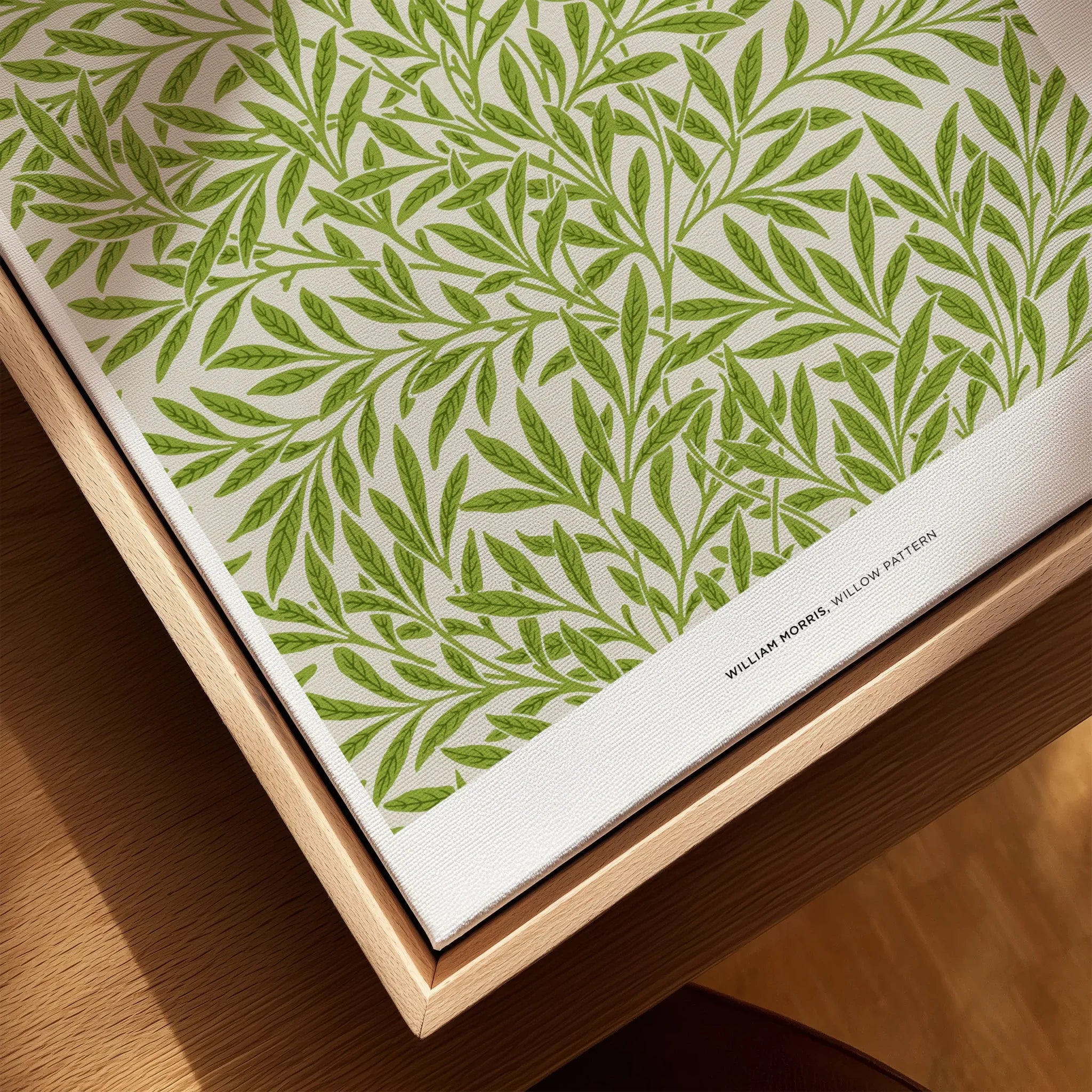 Closeup of framed canvas wall art with green willow leaf pattern in natural wood frame