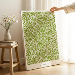 Hand holding canvas wall art with green leaf pattern in a cozy room setting