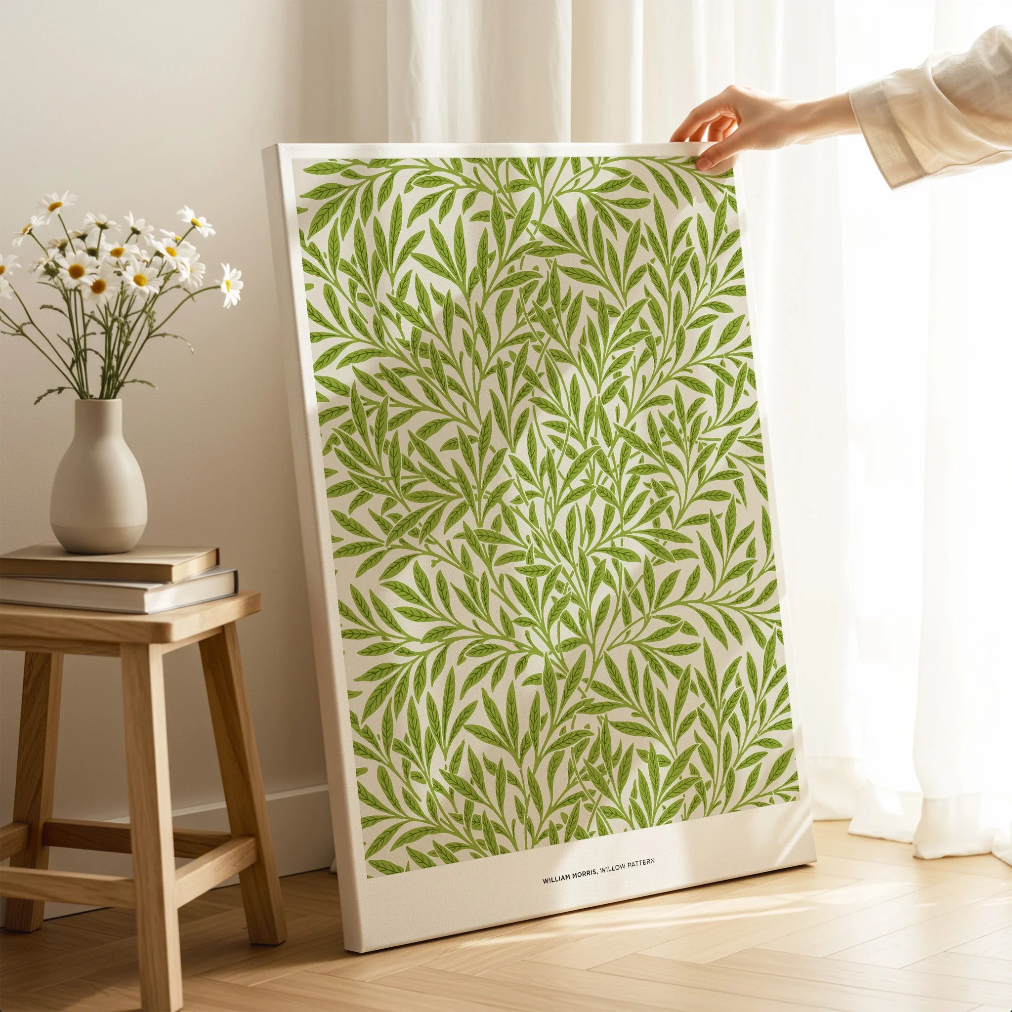 Hand holding canvas wall art with green leaf pattern in a cozy room setting