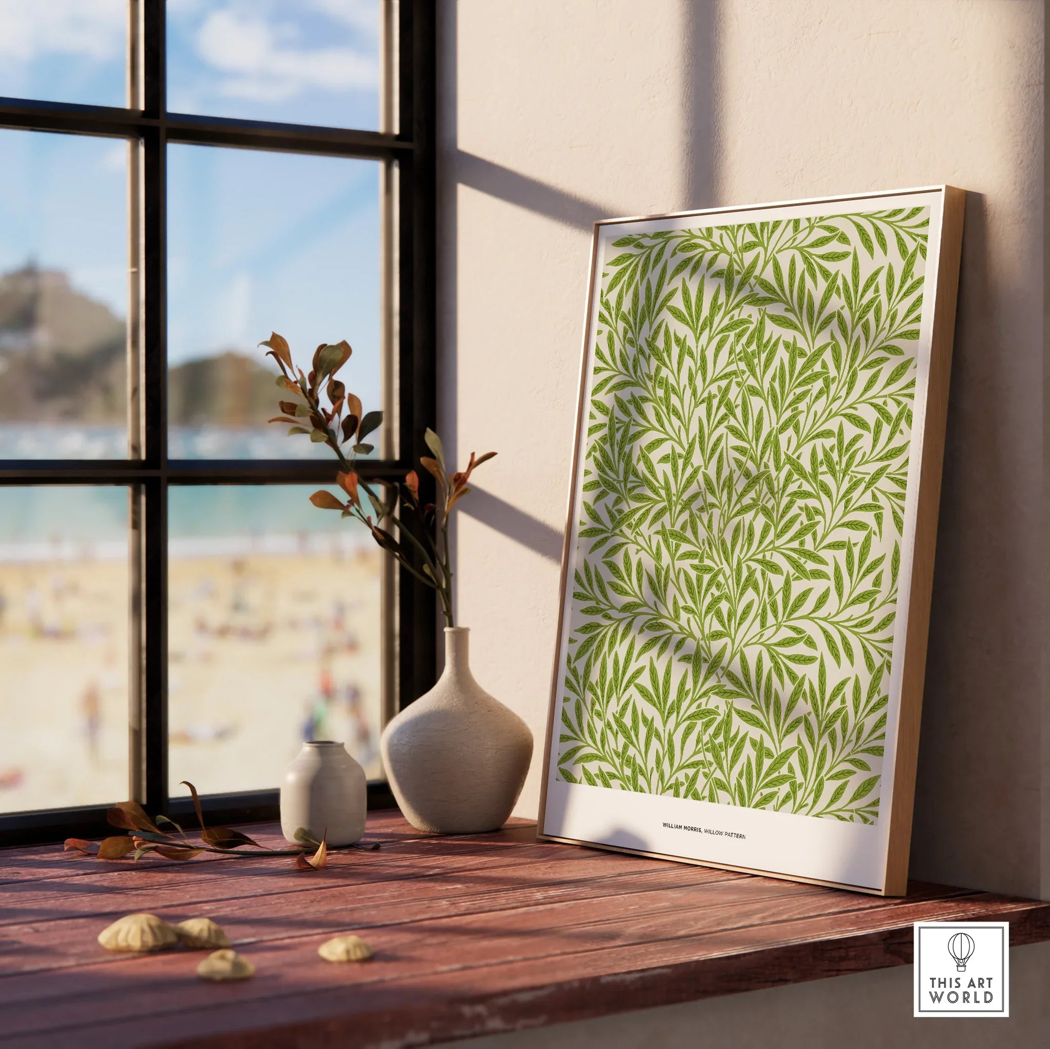 Framed botanical wall art print with green leaf pattern on wood sill beside window with beach view.