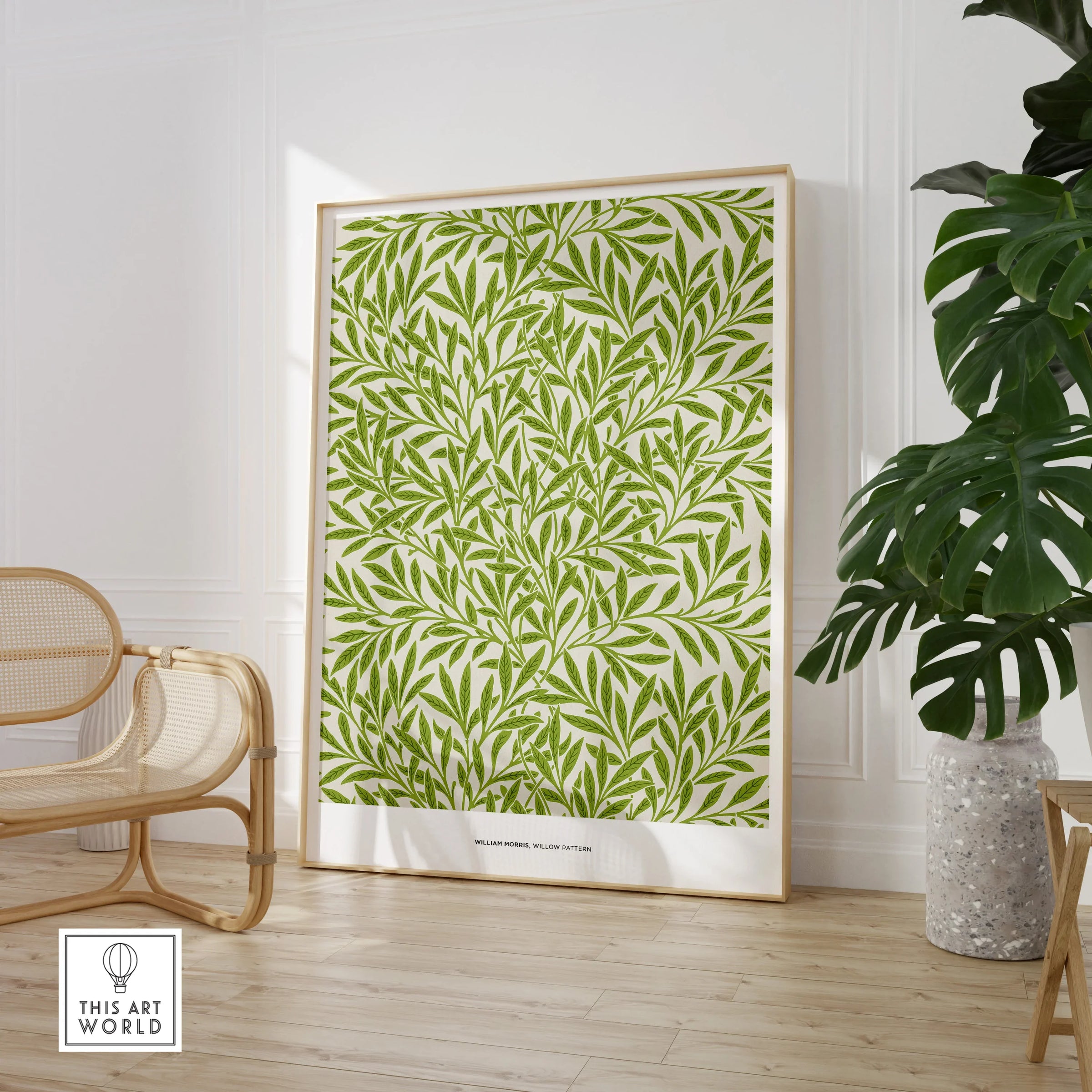 Framed green leafy wall art print in modern room with chair and potted plant, natural decor