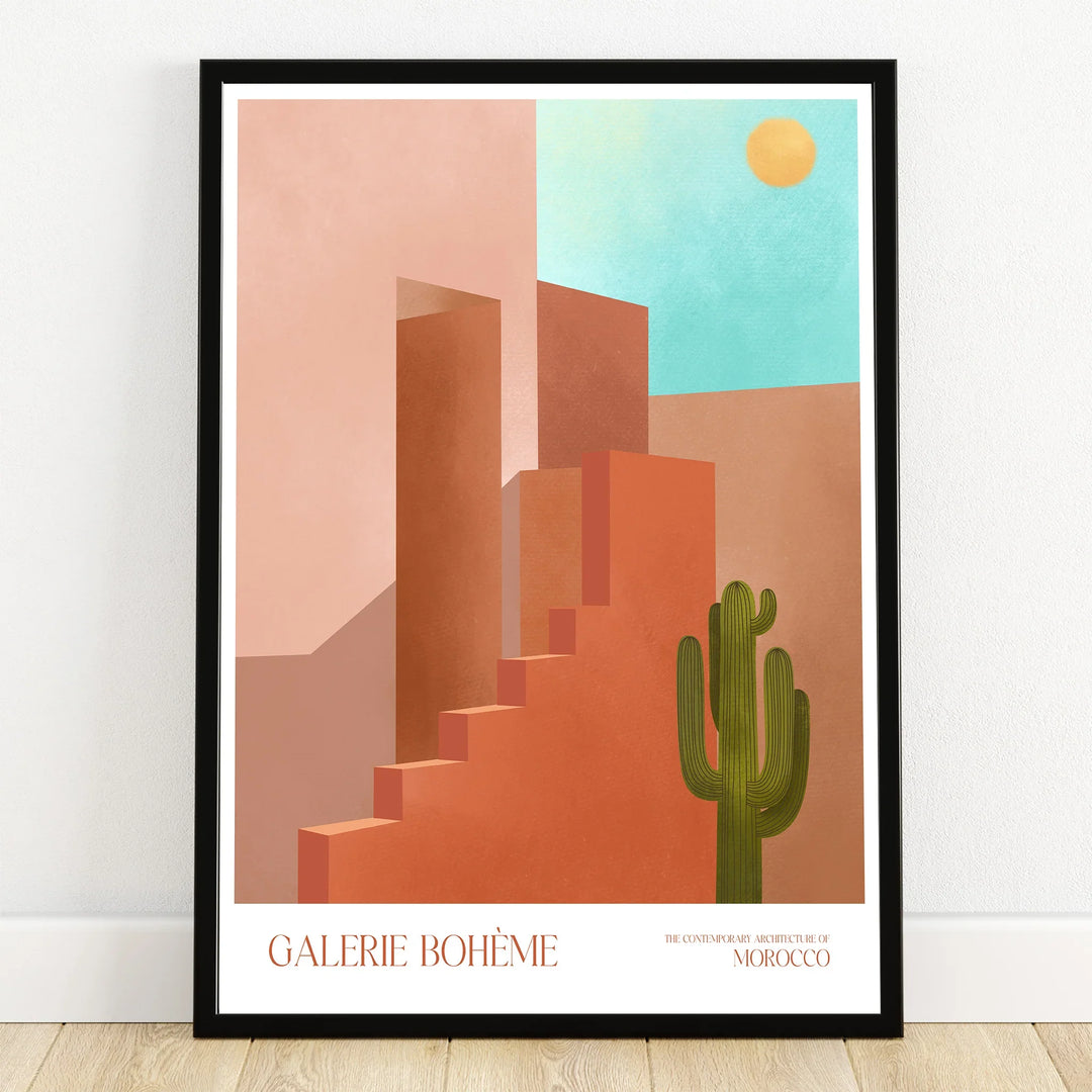 Moroccan architecture wall art print with geometric buildings, cactus, sun, and blue sky in a black frame.