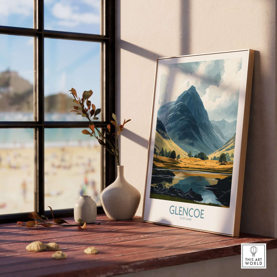 Glencoe travel poster displayed in a stylish interior with a view of mountains and a beach outside the window.