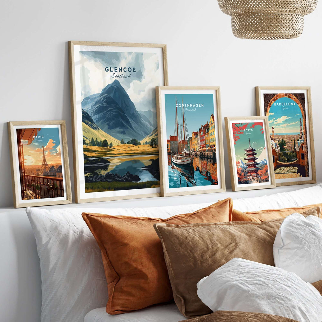 Framed Glencoe travel print and other city prints displayed on a wall above cozy cushions, showcasing travel art.