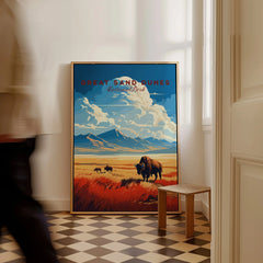 Framed Great Sand Dunes National Park poster with buffalo art on floor, man walking past