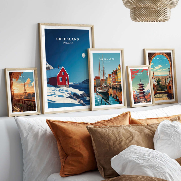 Set of framed travel posters featuring Greenland, Copenhagen, and Barcelona on a cozy bed with decorative pillows.