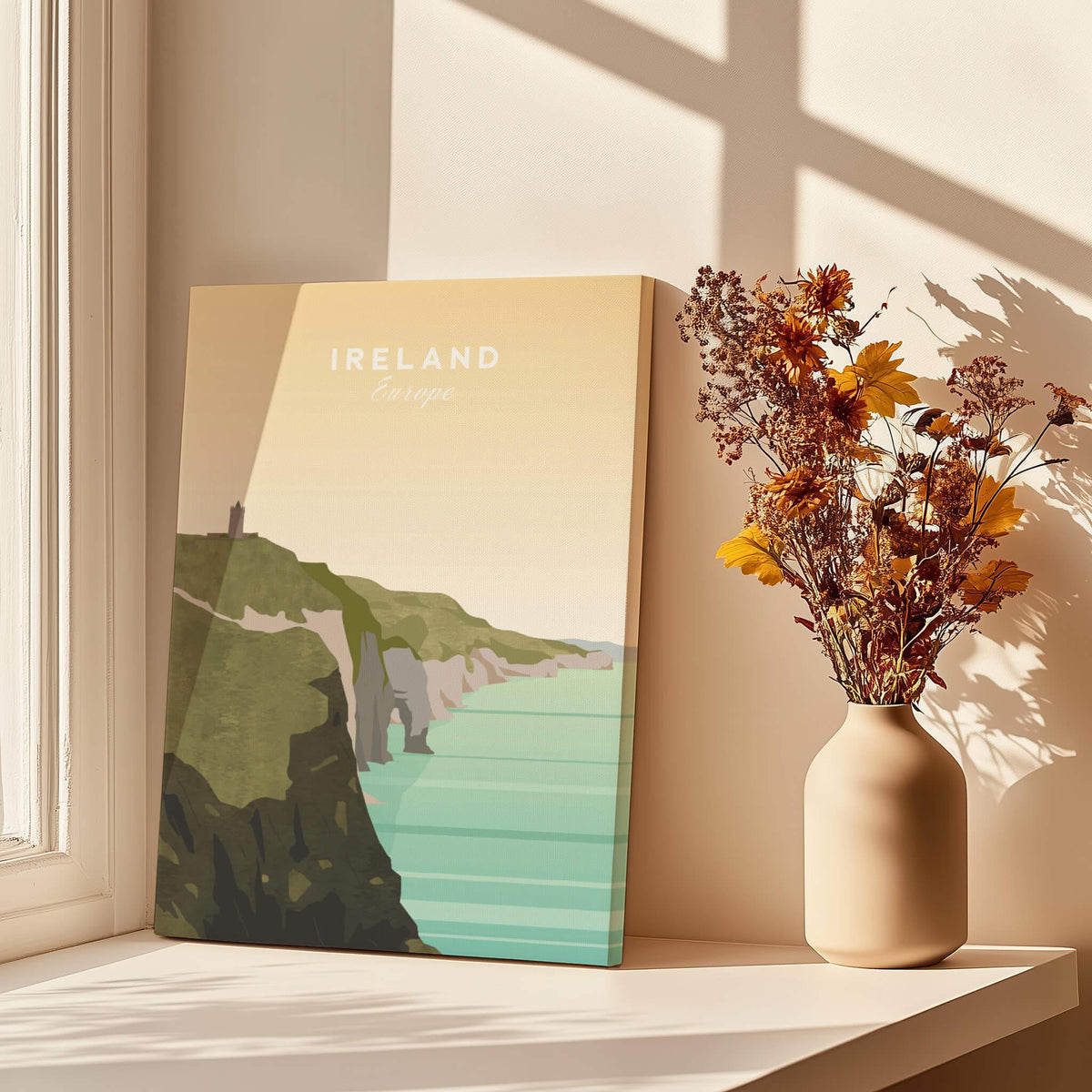 Ireland travel poster wall art with cliffs, ocean view, and vase of dried flowers on windowsill