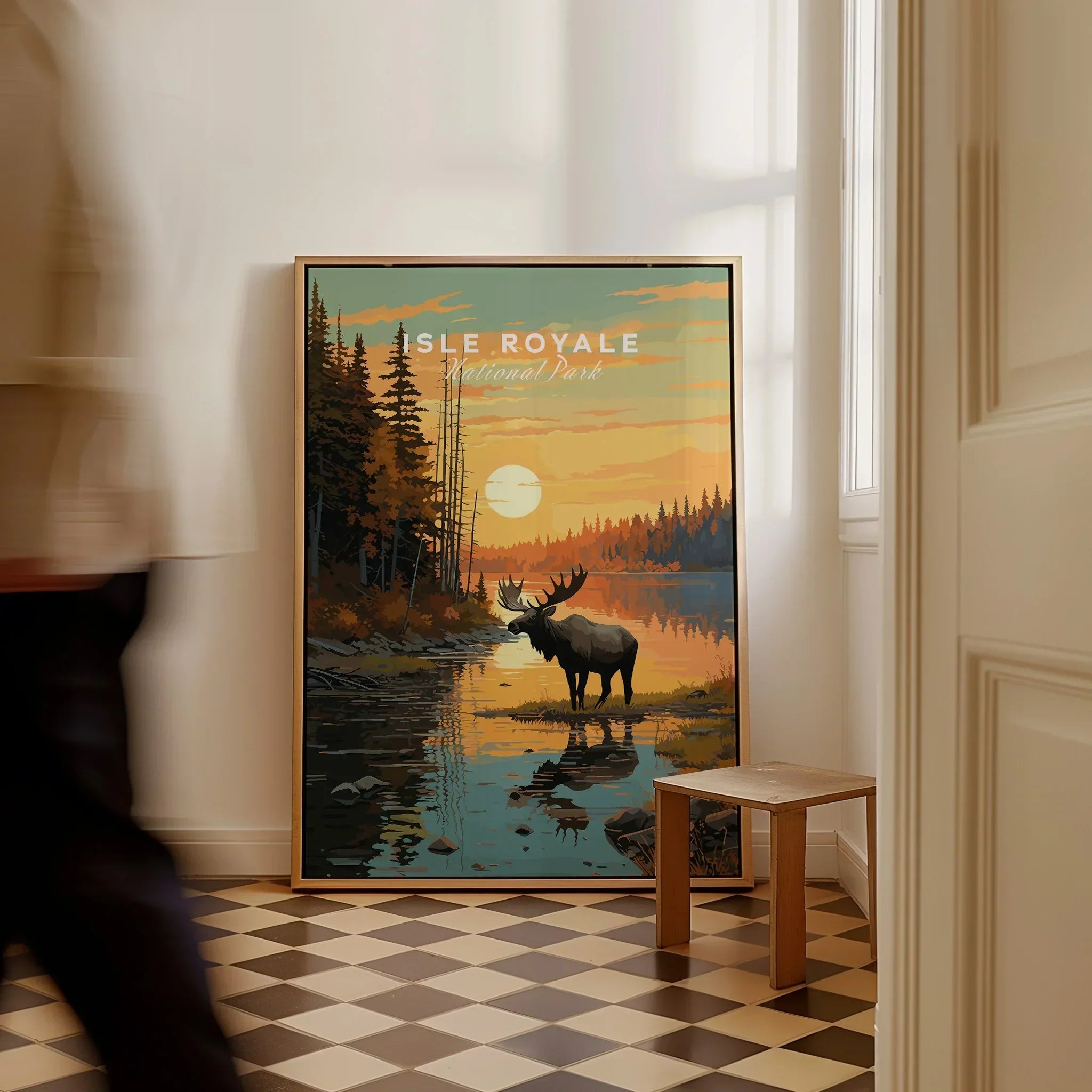 Framed Isle Royale National Park travel poster with moose and sunset, on floor by hallway