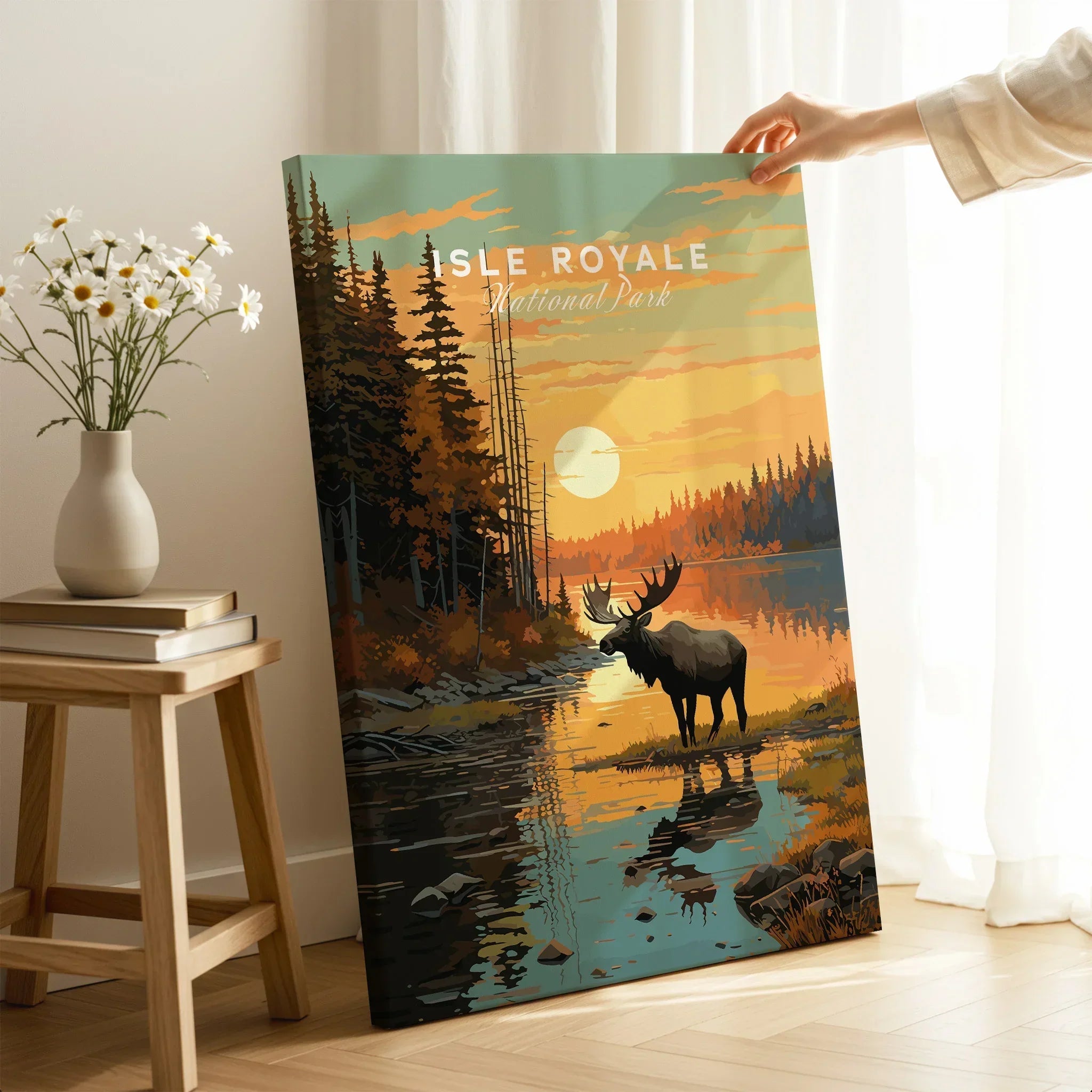 Hand holding Isle Royale National Park art print with moose, forest, and sunset scene