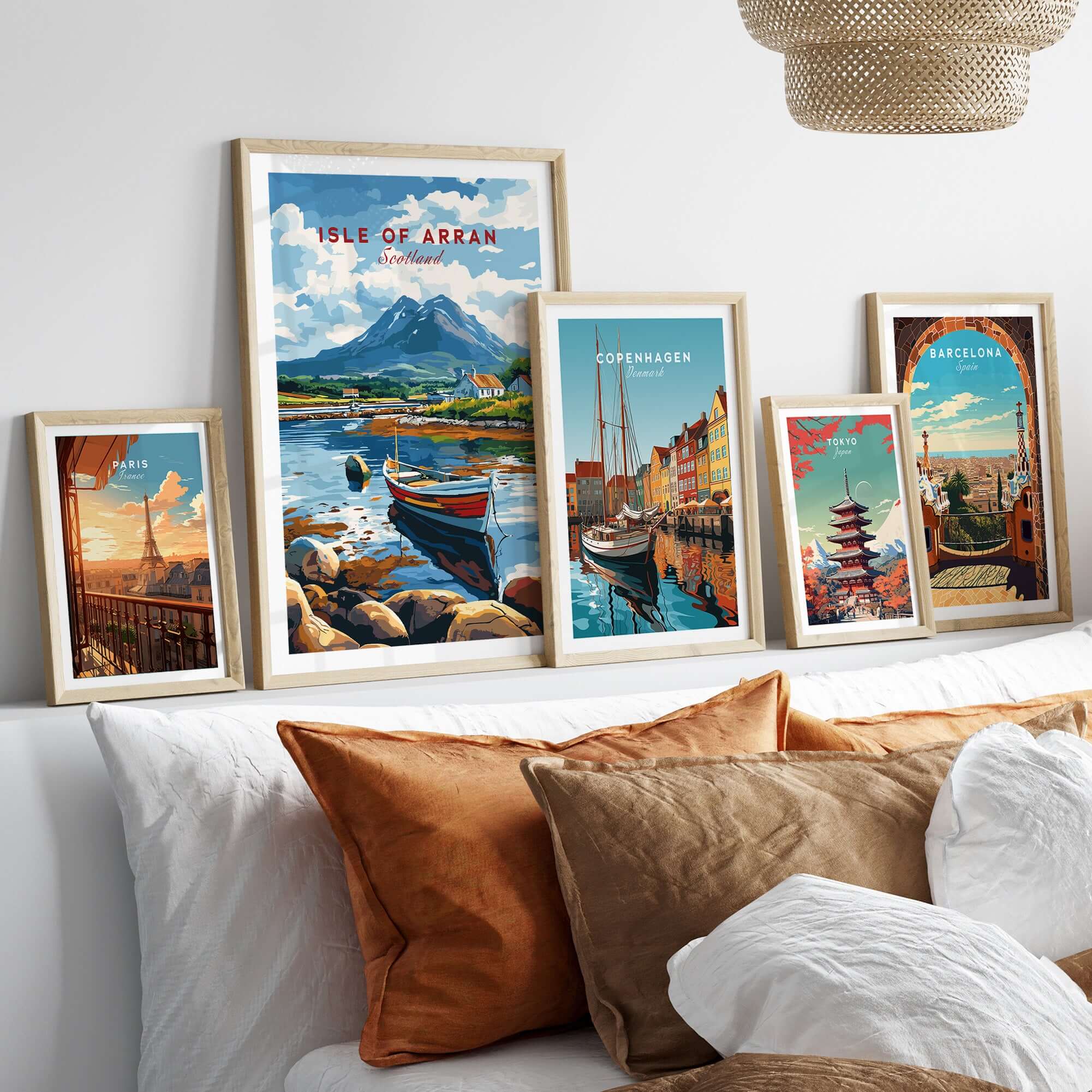Isle of Arran Scotland Travel Print surrounded by other travel prints on a sofa, showcasing vibrant scenic designs.