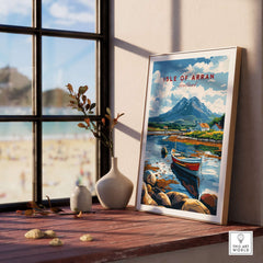 Isle of Arran Scotland Travel Print displayed on a table beside a window with a beach view.
