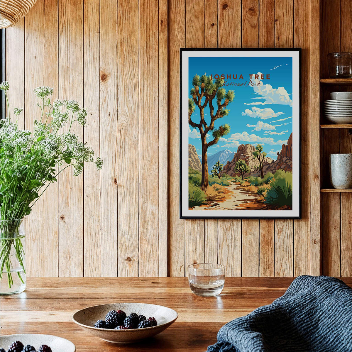 Joshua Tree Poster National Park framed on wooden wall with plants and table setting in background.