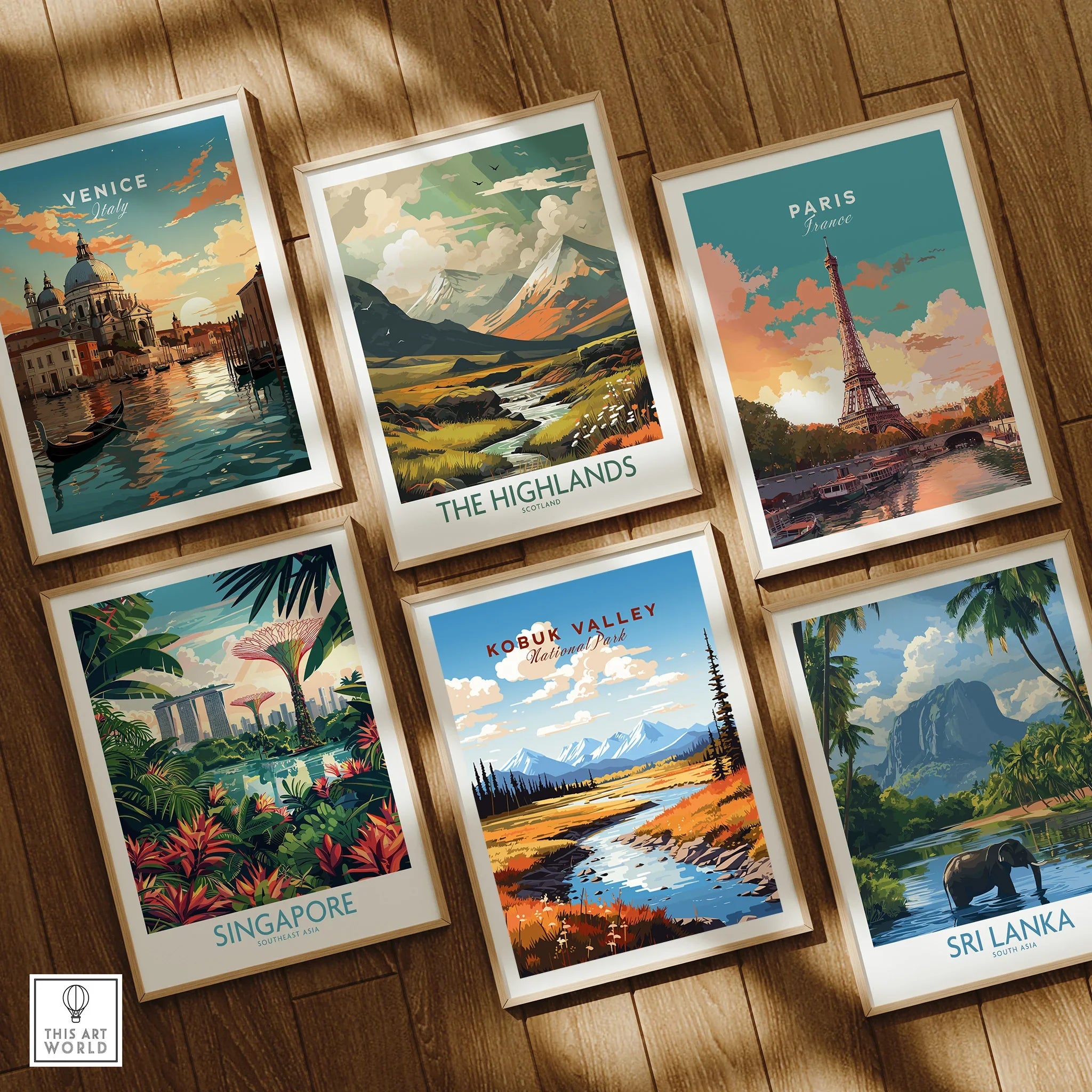 Set of six framed travel art prints featuring Venice, Paris, Singapore, The Highlands, Kobuk Valley, and Sri Lanka displayed on a wooden floor.