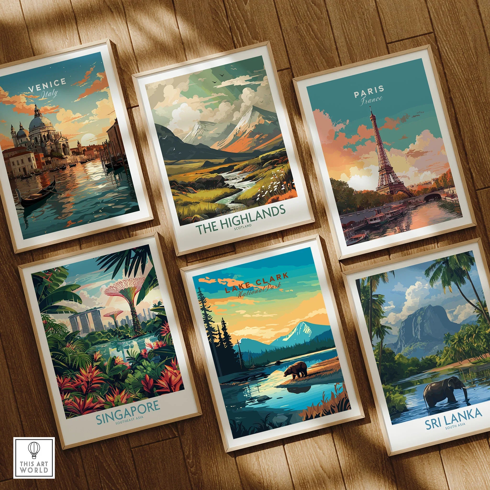 Set of six framed travel posters featuring Venice, Highlands, Paris, Singapore, Lake Clark, and Sri Lanka on a wooden floor.