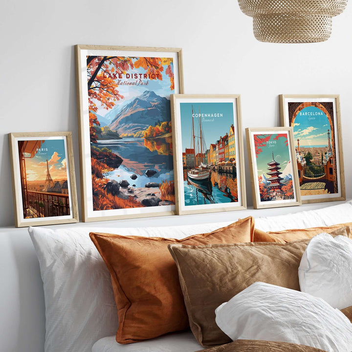 Framed posters of Lake District, Copenhagen, and Barcelona displayed on a wall above a cozy sofa with decorative pillows.