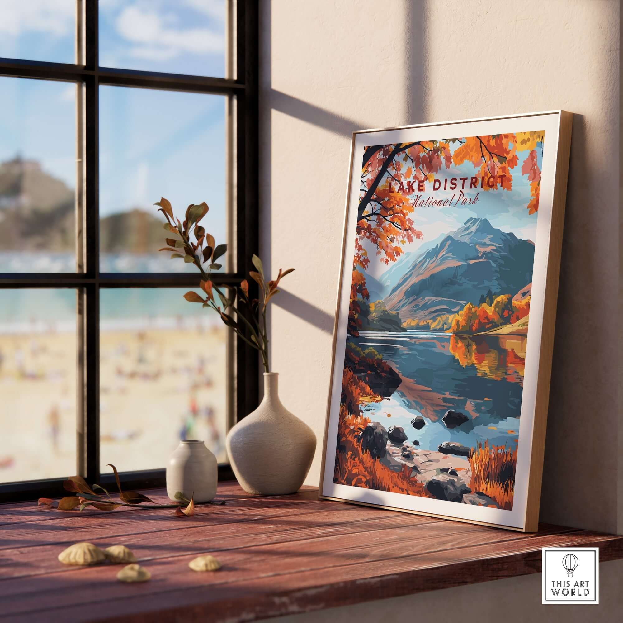 Lake District England Poster displayed on a windowsill with a scenic view of mountains and lakes.