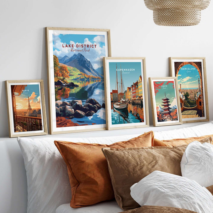 Lake District travel print displayed among other city prints on a cozy couch, showcasing scenic landscapes and vibrant travel art.