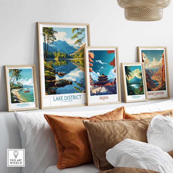 Lake District wall art print among framed travel posters on a cozy sofa, showcasing serene landscapes and vibrant colors.