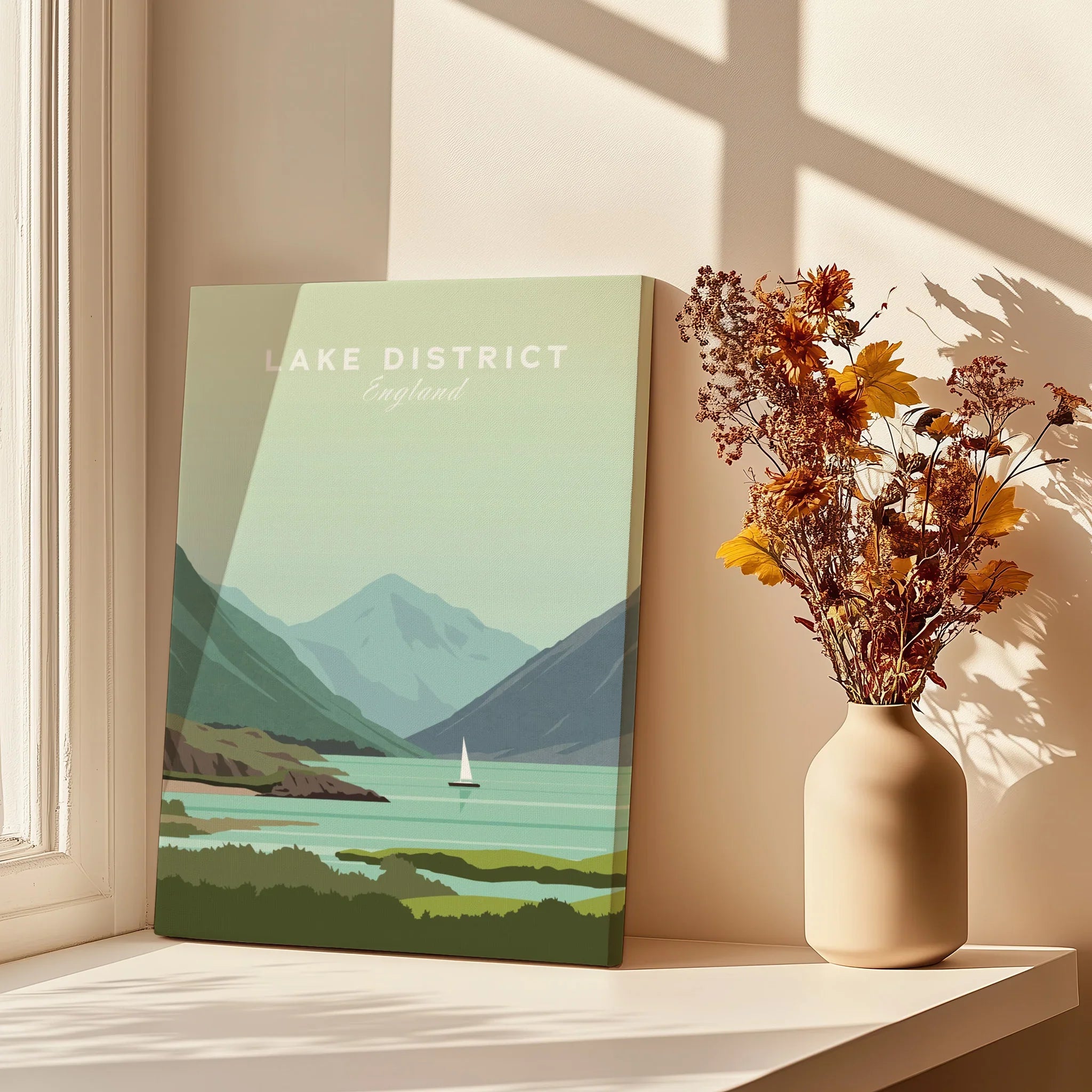 Lake District England travel poster print with mountains, lake, and sailboat, styled on windowsill with dried flowers.