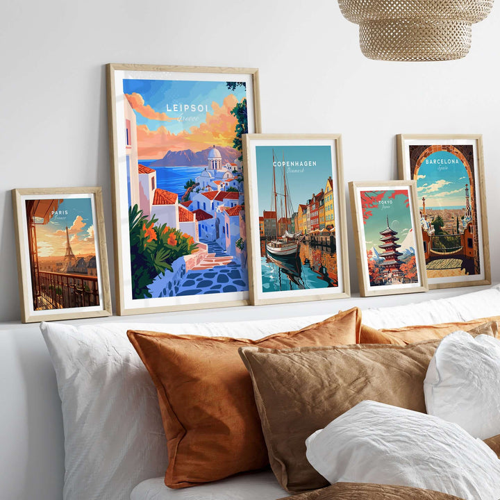 Collection of travel prints including Leipsoi, Copenhagen, and Barcelona displayed on a stylish bed with decorative pillows.