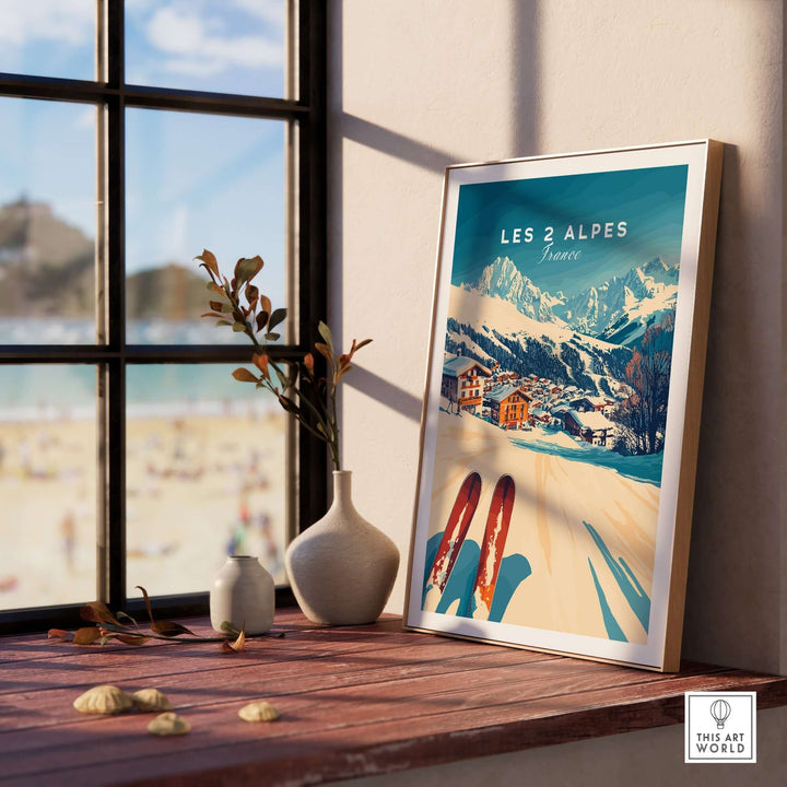 Les 2 Alpes Art Ski Print framed on a wooden table, showcasing vibrant ski-themed decor with a stunning mountain backdrop.