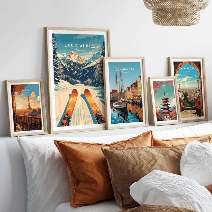 Les 2 Alpes ski poster framed among travel-themed art prints on a cozy bed with decorative pillows.