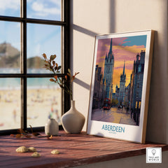Aberdeen Scotland travel poster print with city skyline, sunset, and red bus, displayed on a windowsill for home decor.