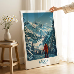 Arosa Wall Art Print Switzerland displayed indoors, showcasing snowy mountains and a skier in a red jacket.