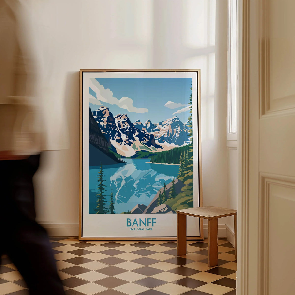 Framed Banff National Park travel poster with mountains and lake, resting on floor in bright hallway