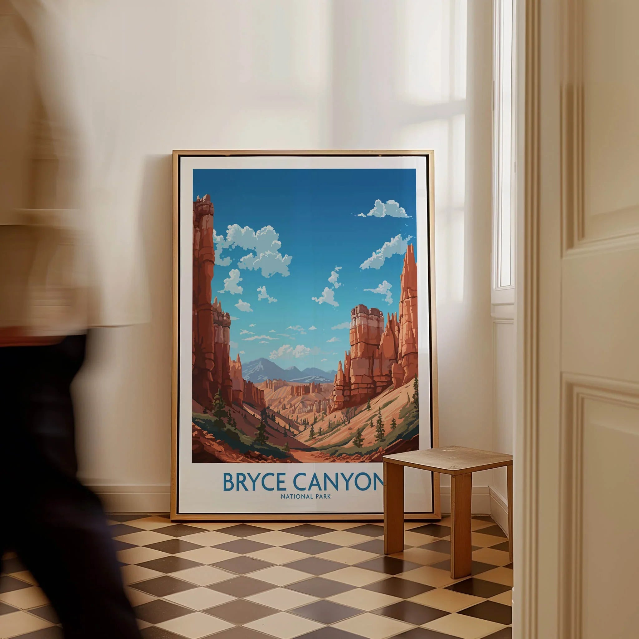 Framed Bryce Canyon National Park art print on floor beside a wooden stool, man walking past.