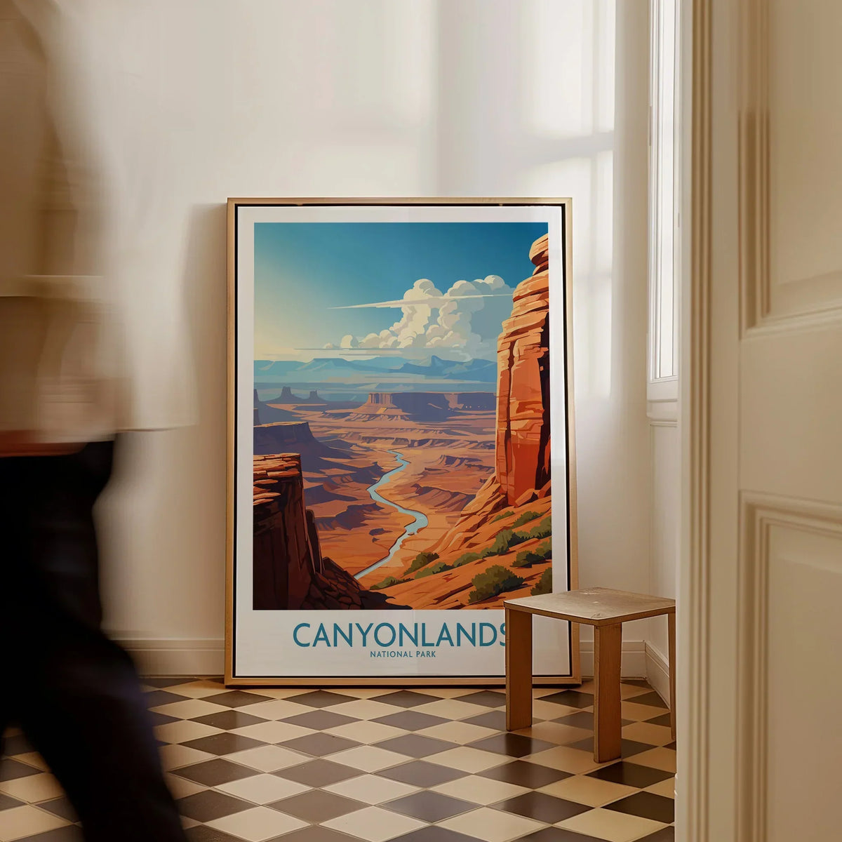 Framed Canyonlands National Park travel poster on floor in bright hallway, man walking past