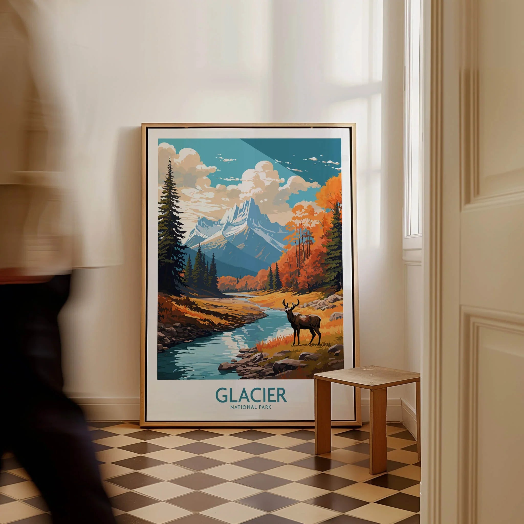 Framed Glacier National Park travel poster with mountain scenery on floor, man walking past.