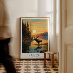 Framed Isle Royale National Park travel poster with moose at sunset on floor, man walking past