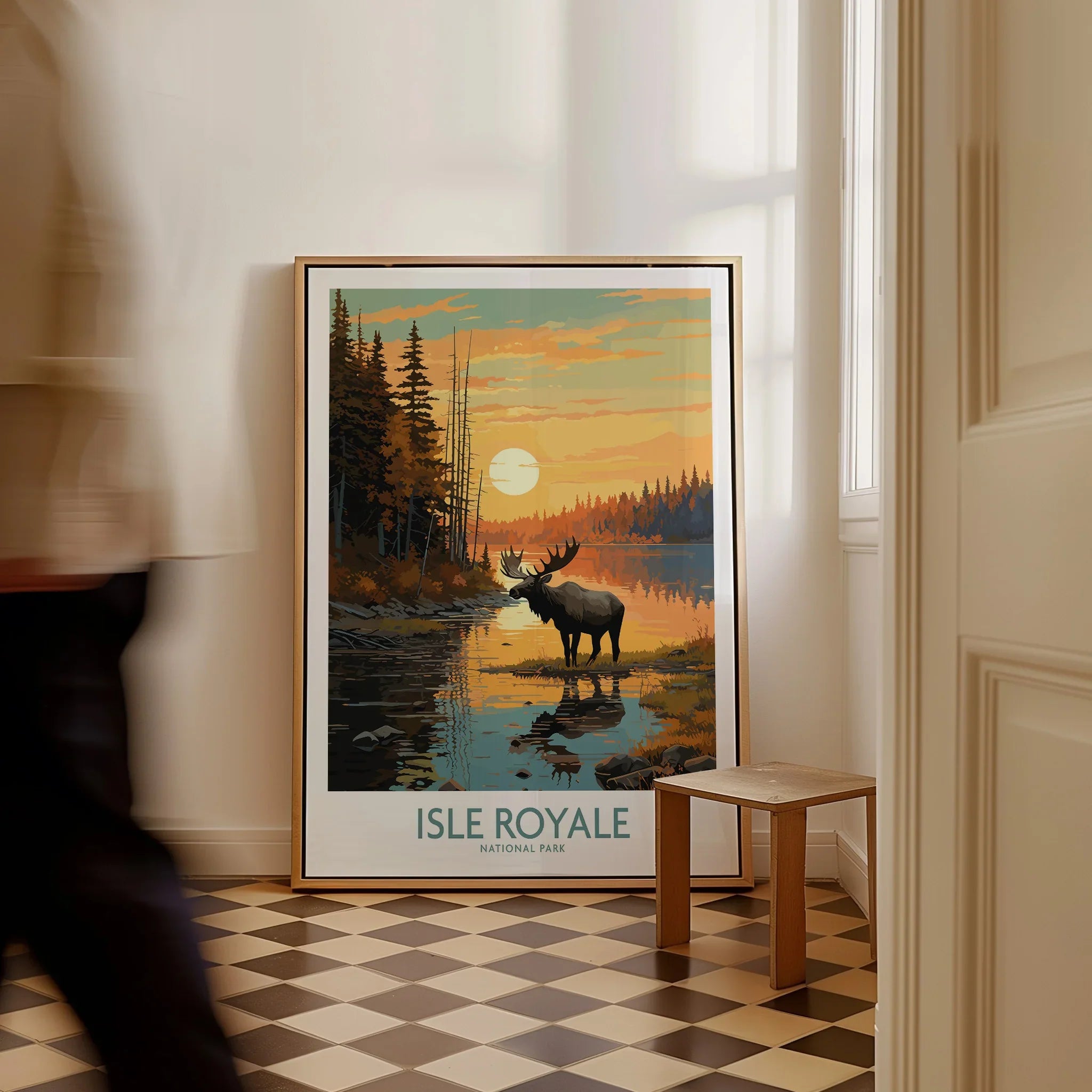 Framed Isle Royale National Park travel poster with moose at sunset on floor, man walking past