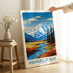 Hand holding Wrangell-St. Elias National Park print with mountain landscape in cozy room