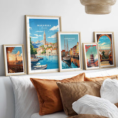 Framed Makarska and travel posters on a stylish bed with decorative pillows, showcasing vibrant Croatian art.