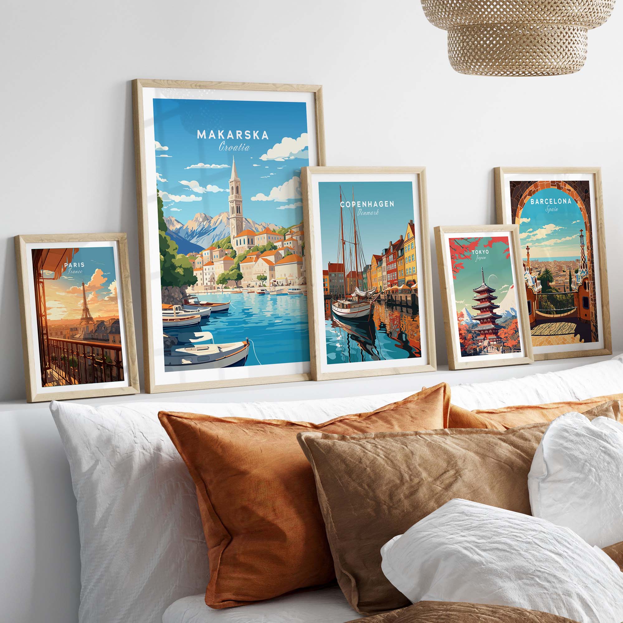 Framed Makarska and travel posters on a stylish bed with decorative pillows, showcasing vibrant Croatian art.