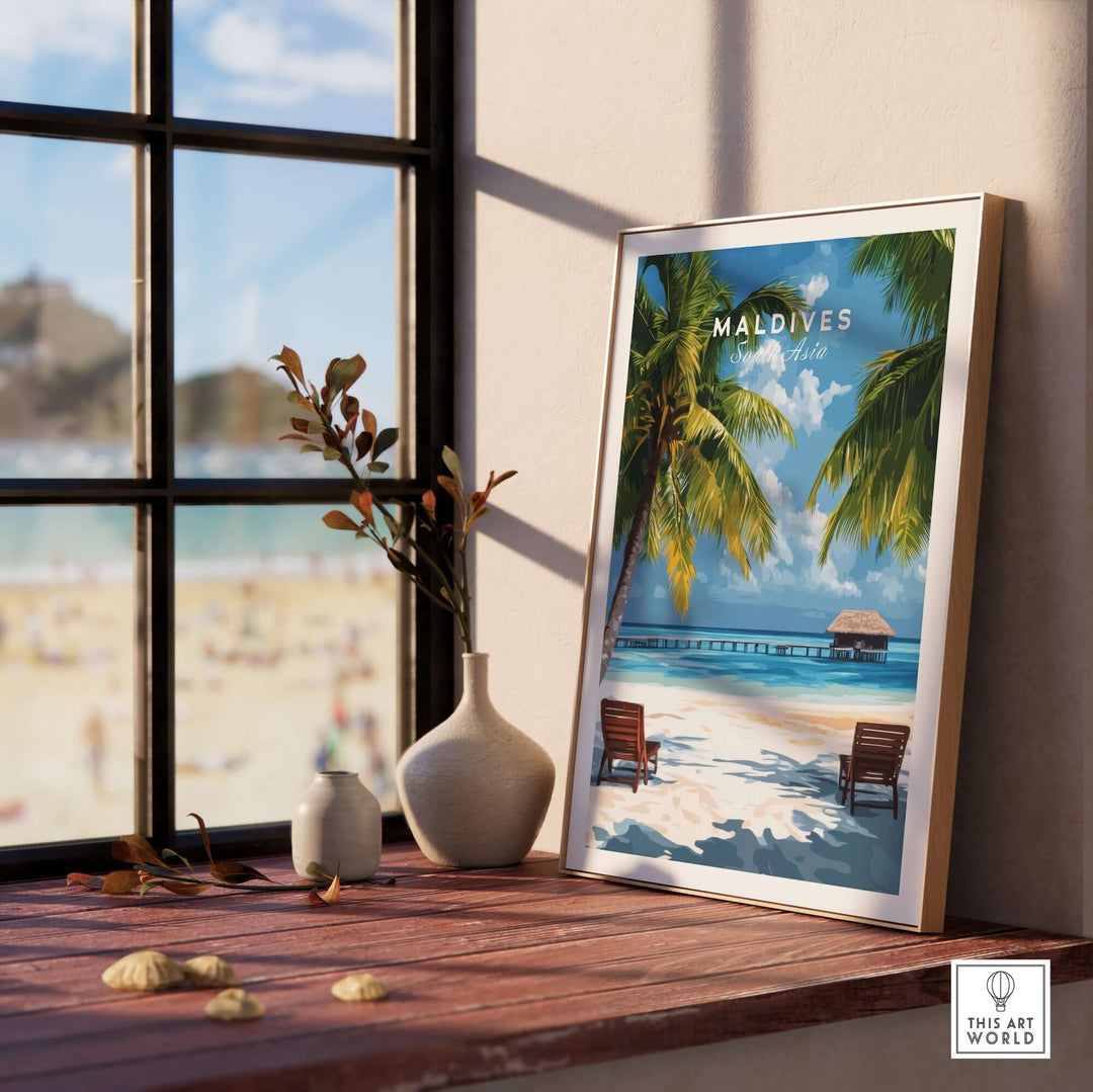 Maldives poster featuring a tropical beach scene with palm trees and lounge chairs, displayed on a windowsill.