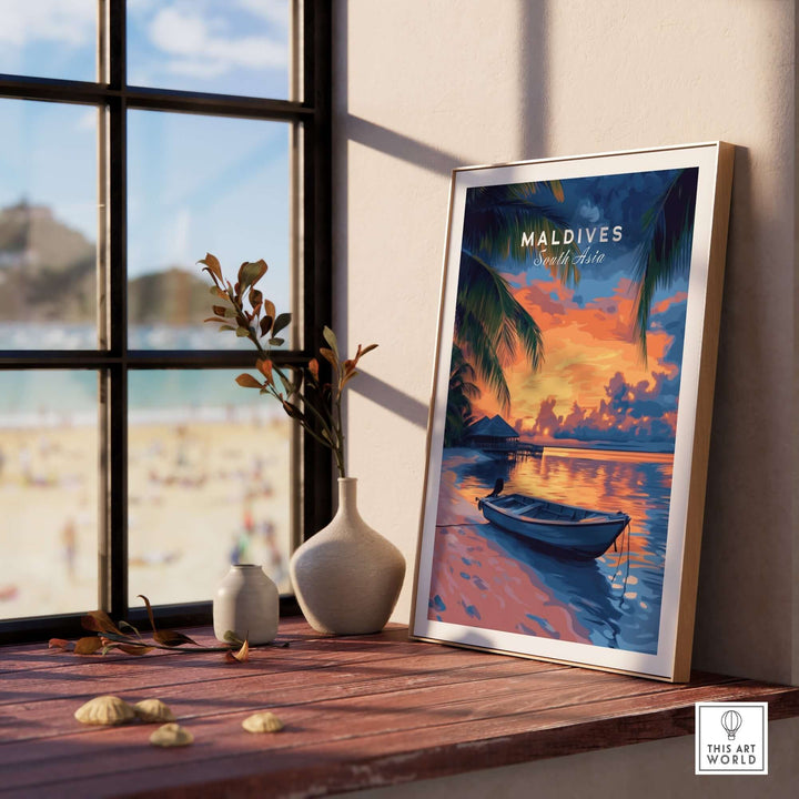 Maldives travel print showcasing a vibrant sunset over the ocean, framed and displayed by a window.