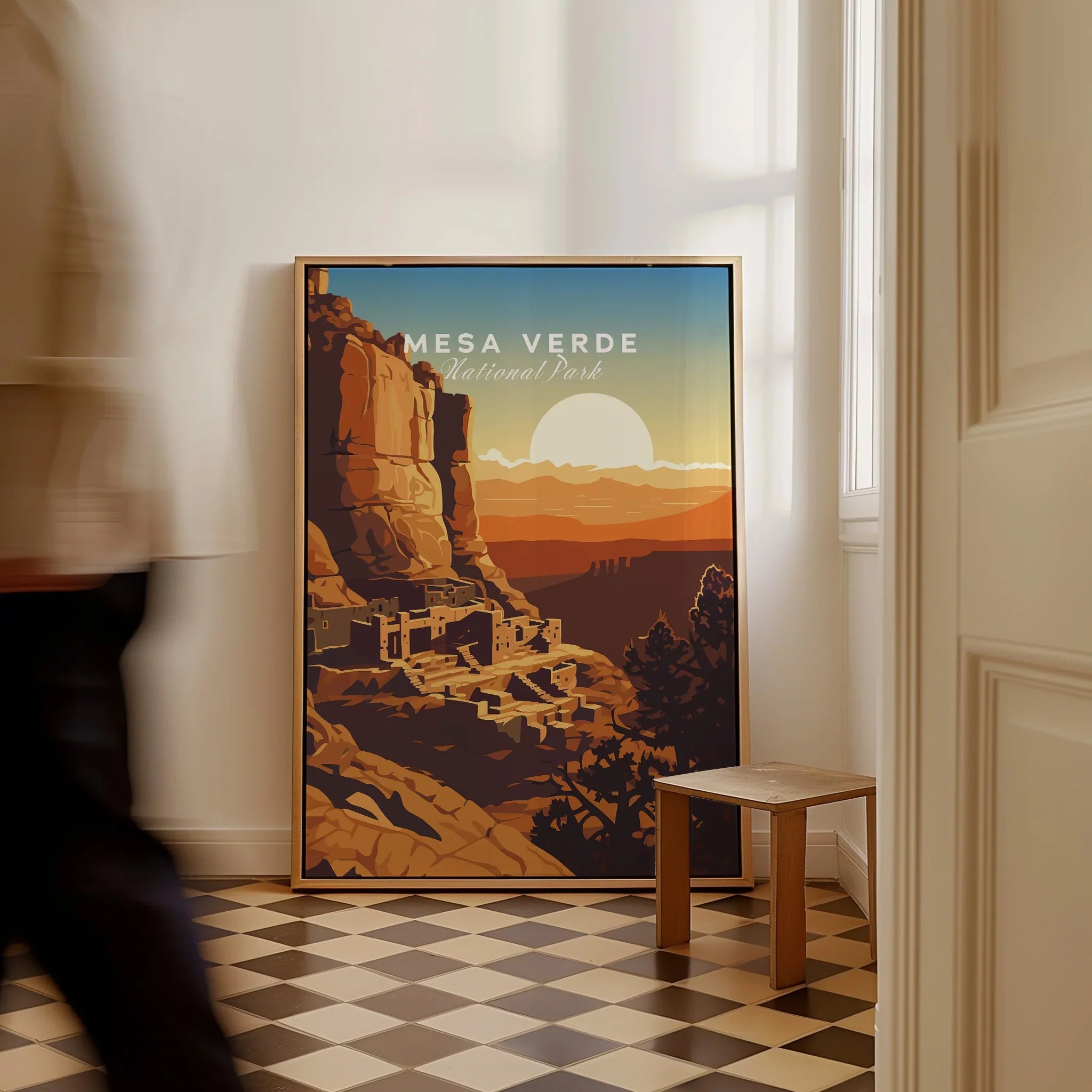 Framed Mesa Verde National Park travel poster on floor in modern hallway, man walking past