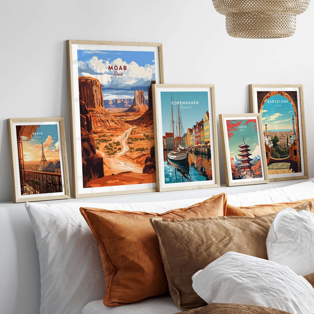 Moab Travel Print surrounded by other travel prints on a stylish wall above a cozy bed with decorative pillows.