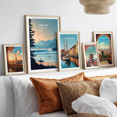 Set of five framed travel posters featuring Tofino, Paris, Copenhagen, Tokyo, and Barcelona above bed