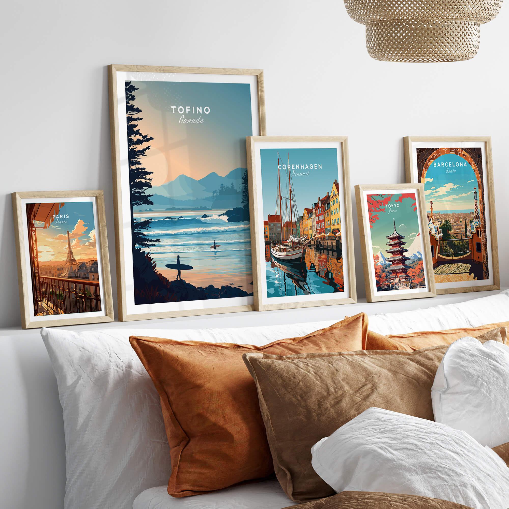 Set of five framed travel posters featuring Tofino, Paris, Copenhagen, Tokyo, and Barcelona above bed