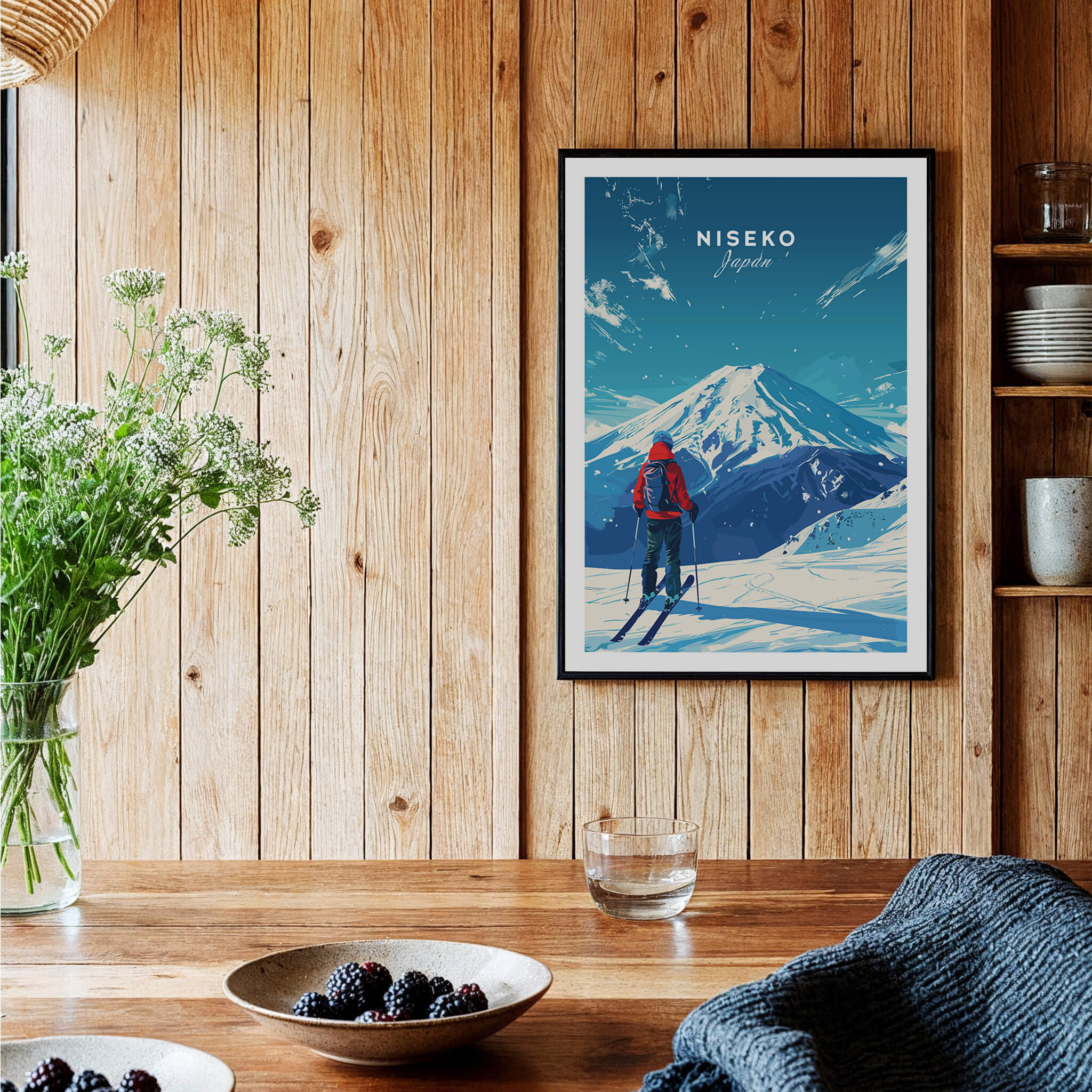 Niseko Travel Print - Japan displayed on a wooden wall above a table, showcasing stunning ski slopes and winter scenery.