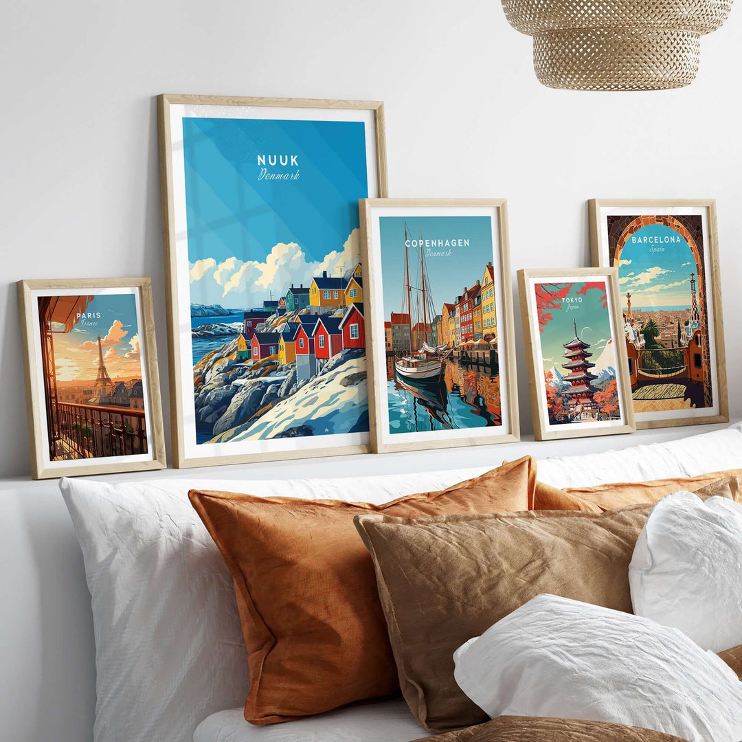 Collection of framed Nuuk, Copenhagen, and Barcelona travel prints displayed on a cozy couch with decorative pillows.