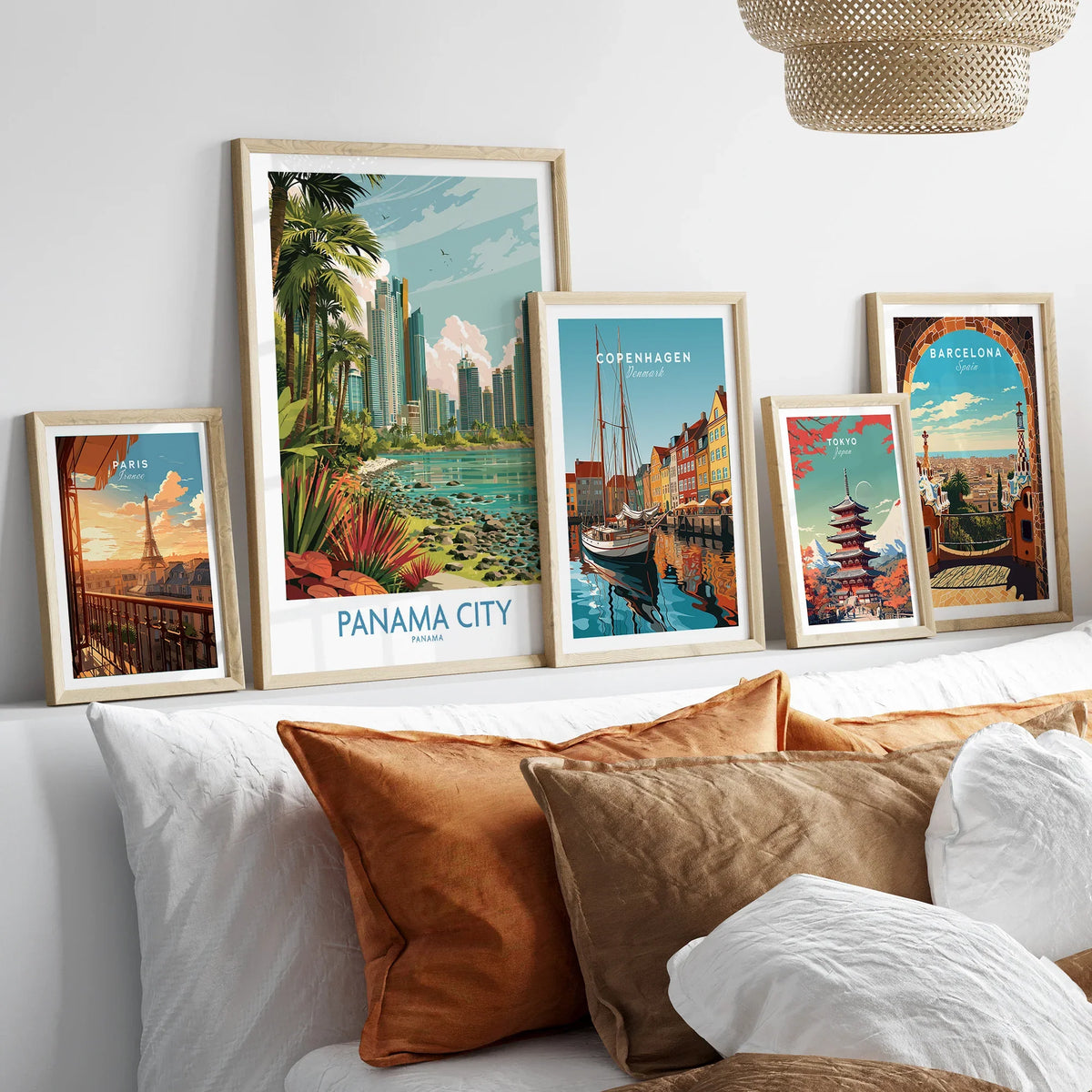 Framed travel posters of Paris, Panama City, Copenhagen, Tokyo, and Barcelona displayed above a bed with cozy pillows.