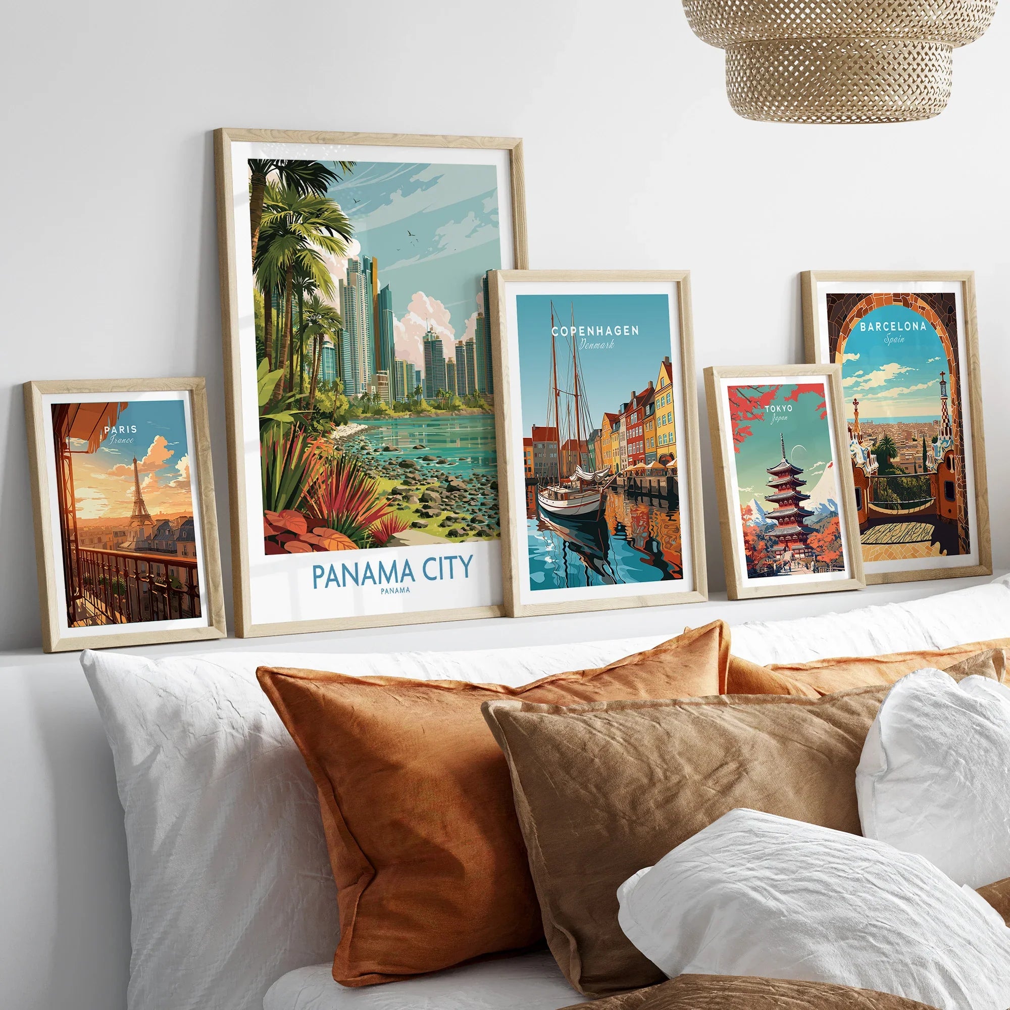 Framed travel posters of Paris, Panama City, Copenhagen, Tokyo, and Barcelona displayed above a bed with cozy pillows.