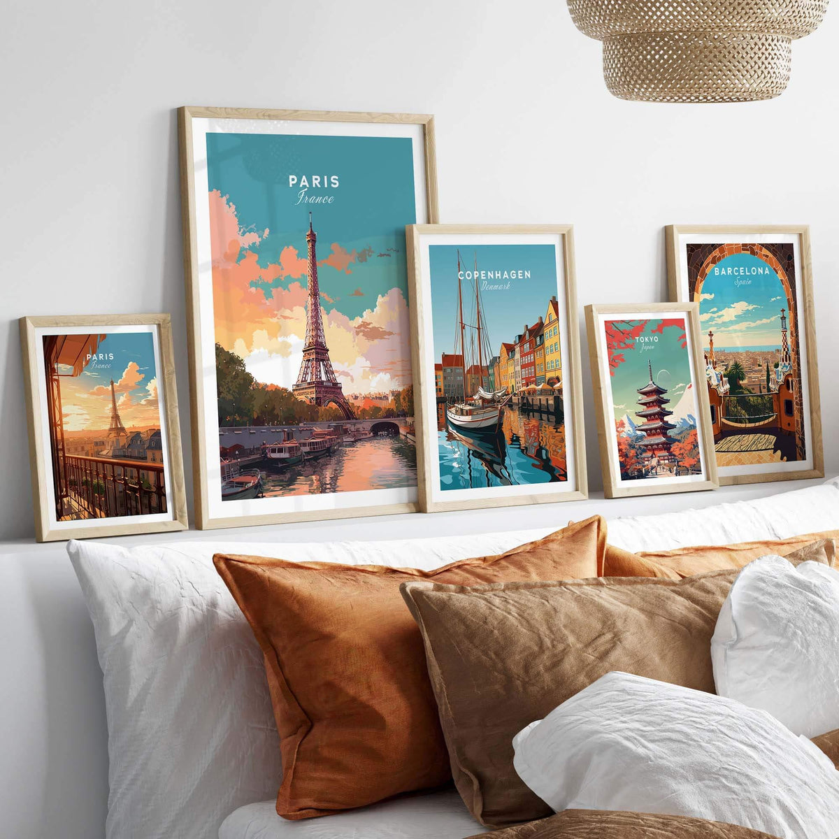 Art prints of Paris, Copenhagen, and Barcelona displayed in stylish frames on a cozy bed backdrop.