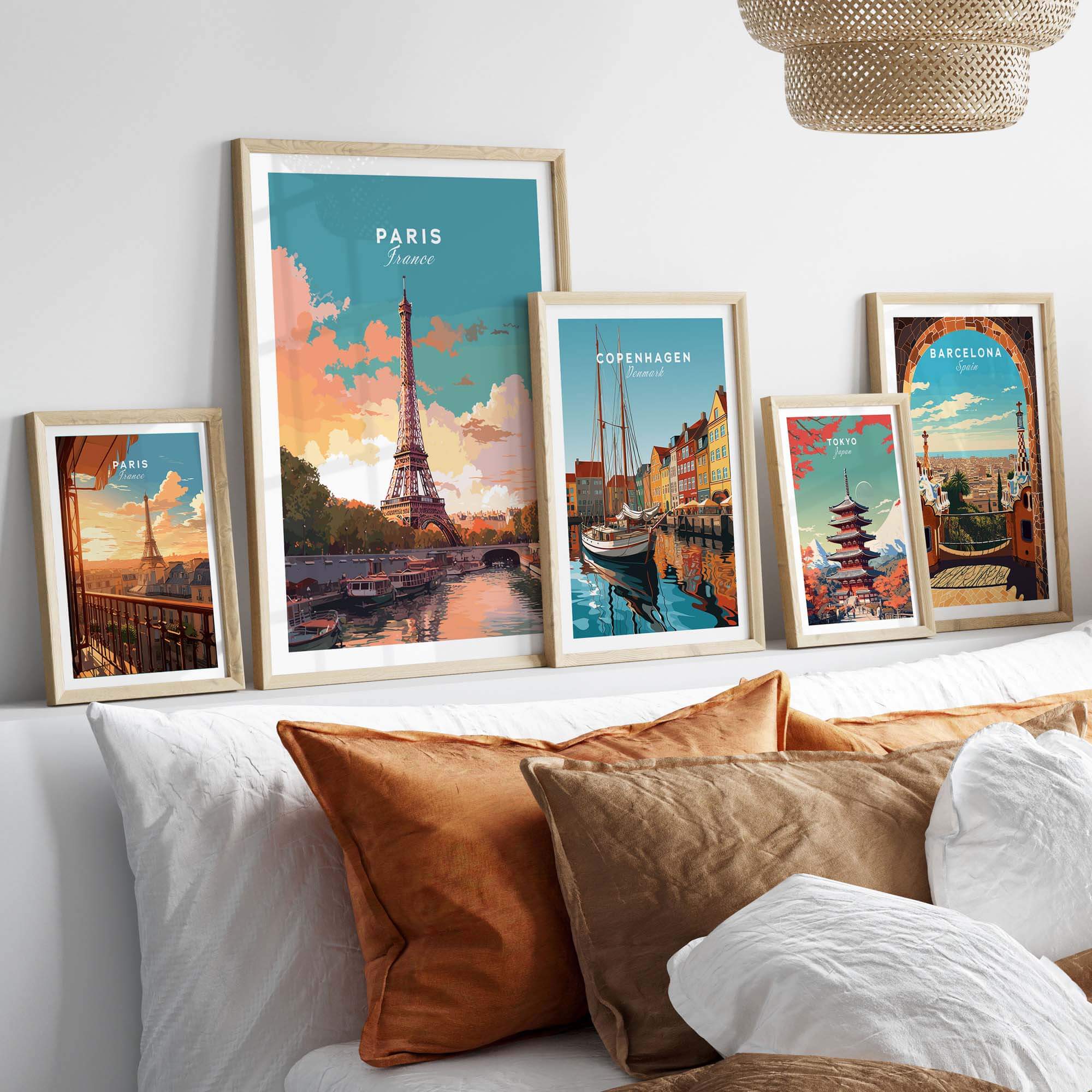 Art prints of Paris, Copenhagen, and Barcelona displayed in stylish frames on a cozy bed backdrop.