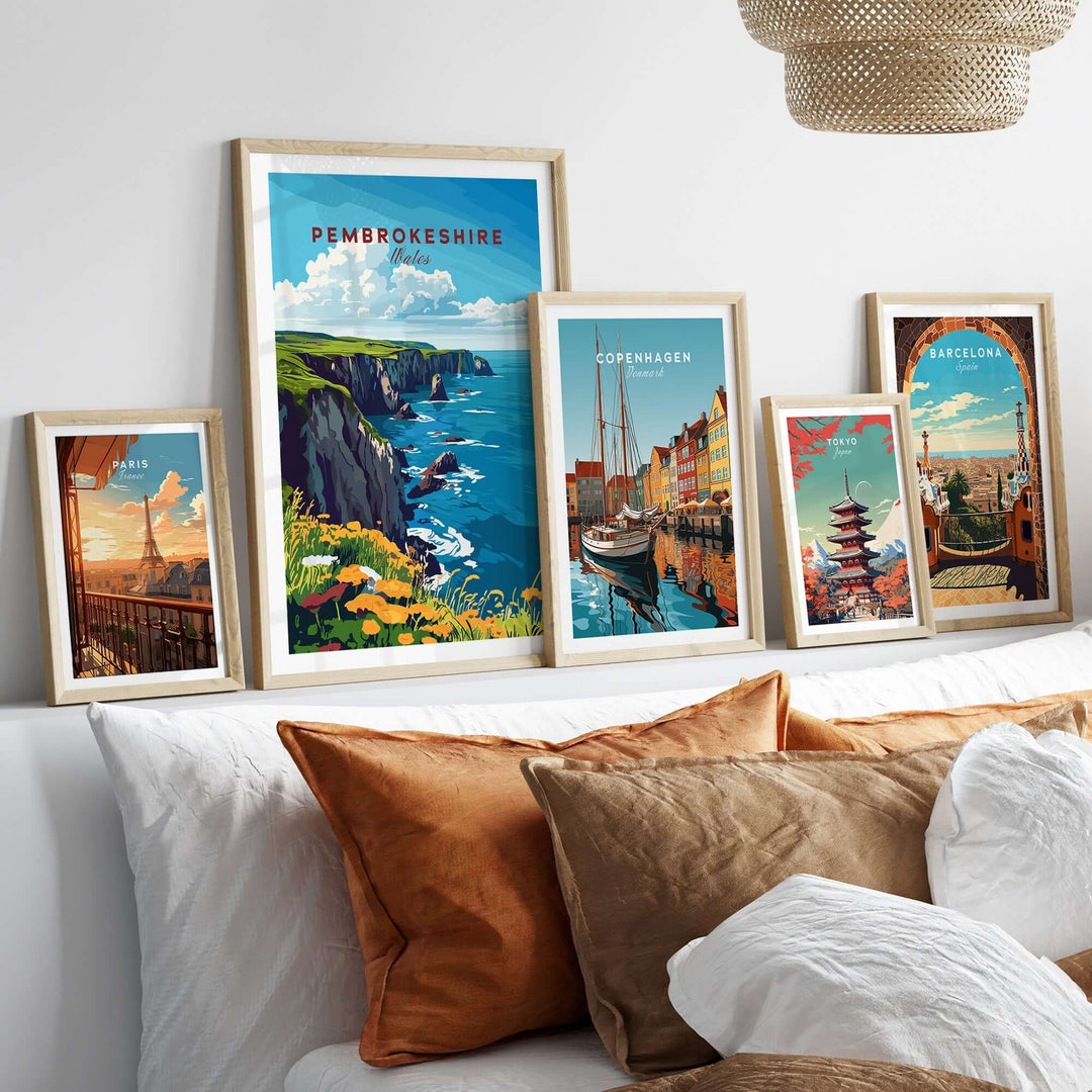 Framed travel prints of Pembrokeshire, Copenhagen, and Barcelona displayed on a cozy sofa with decorative pillows.